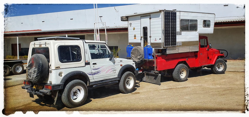 toyota pickup towing a suzuki jimy with demountable on the back